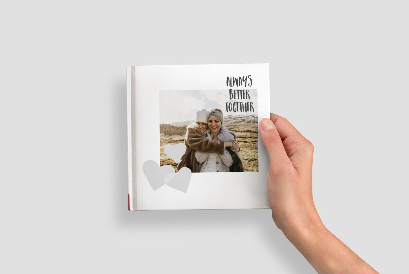 Een hand houdt een open fotoboek met een foto en tekst op de cover