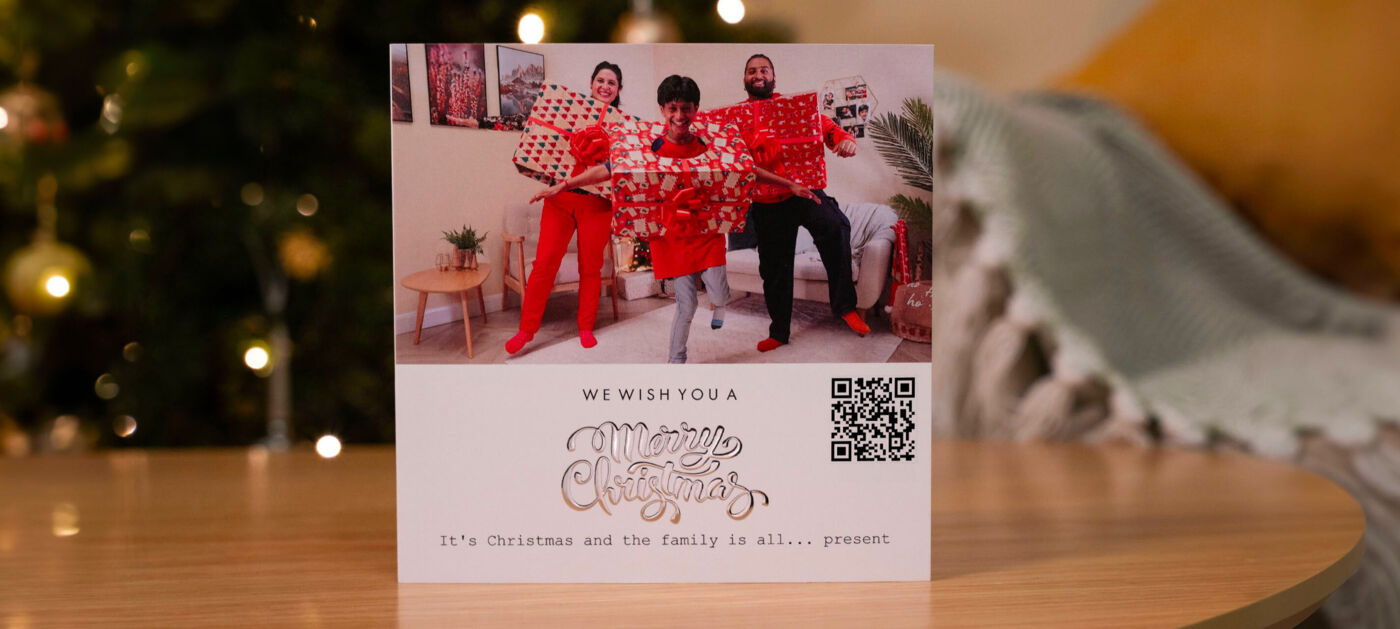 Drie vrolijke mensen in rode outfits met cadeaus en een kerstboodschap