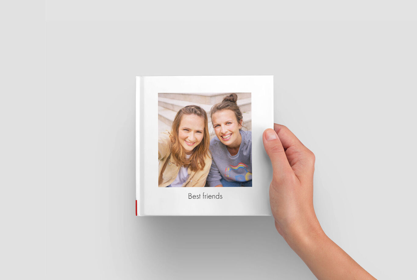 Een hand houdt een CEWE fotoboek met 'Best friends', een persoonlijke herinnering.